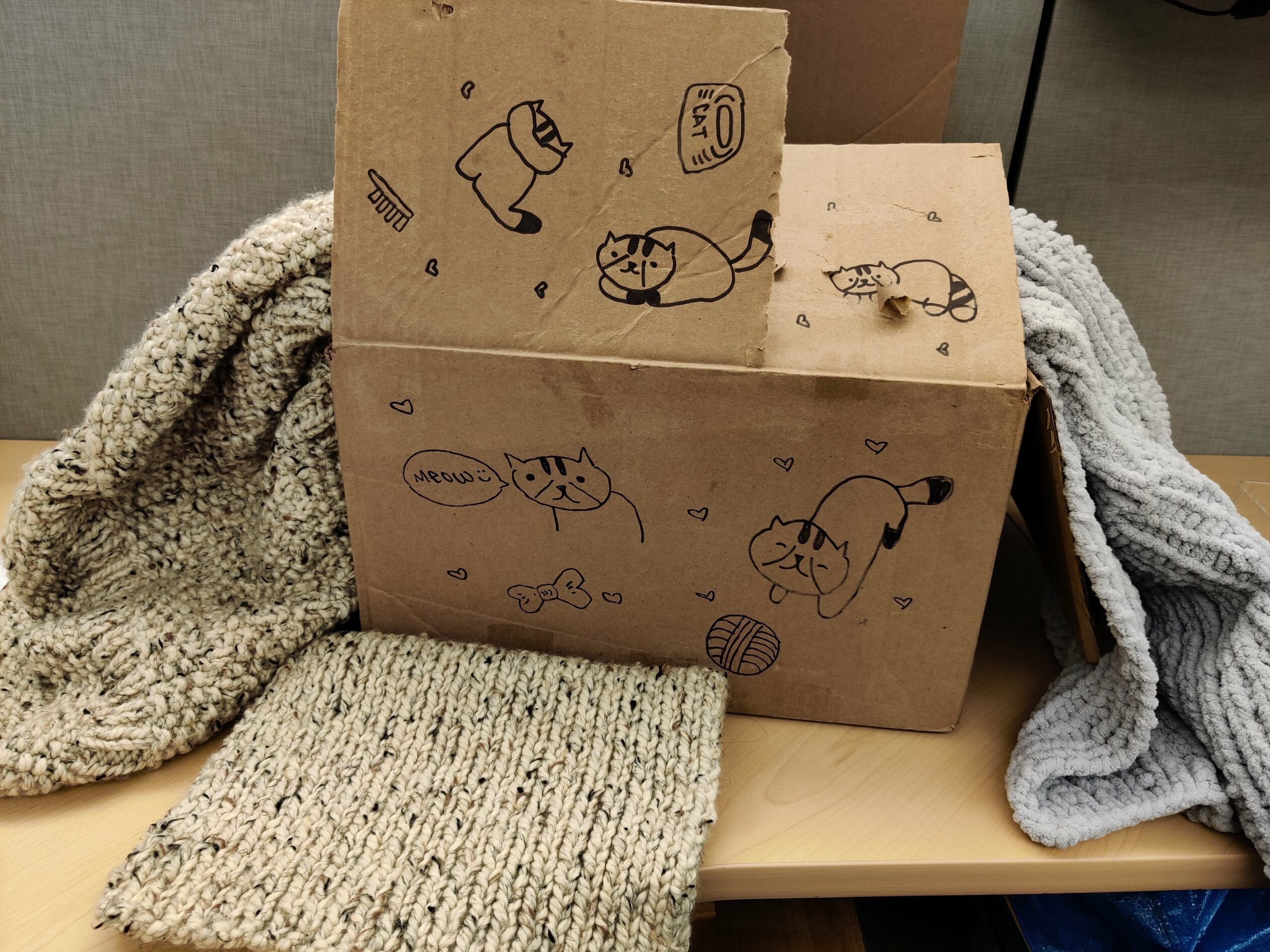 Three knit blankets and a cardboard box