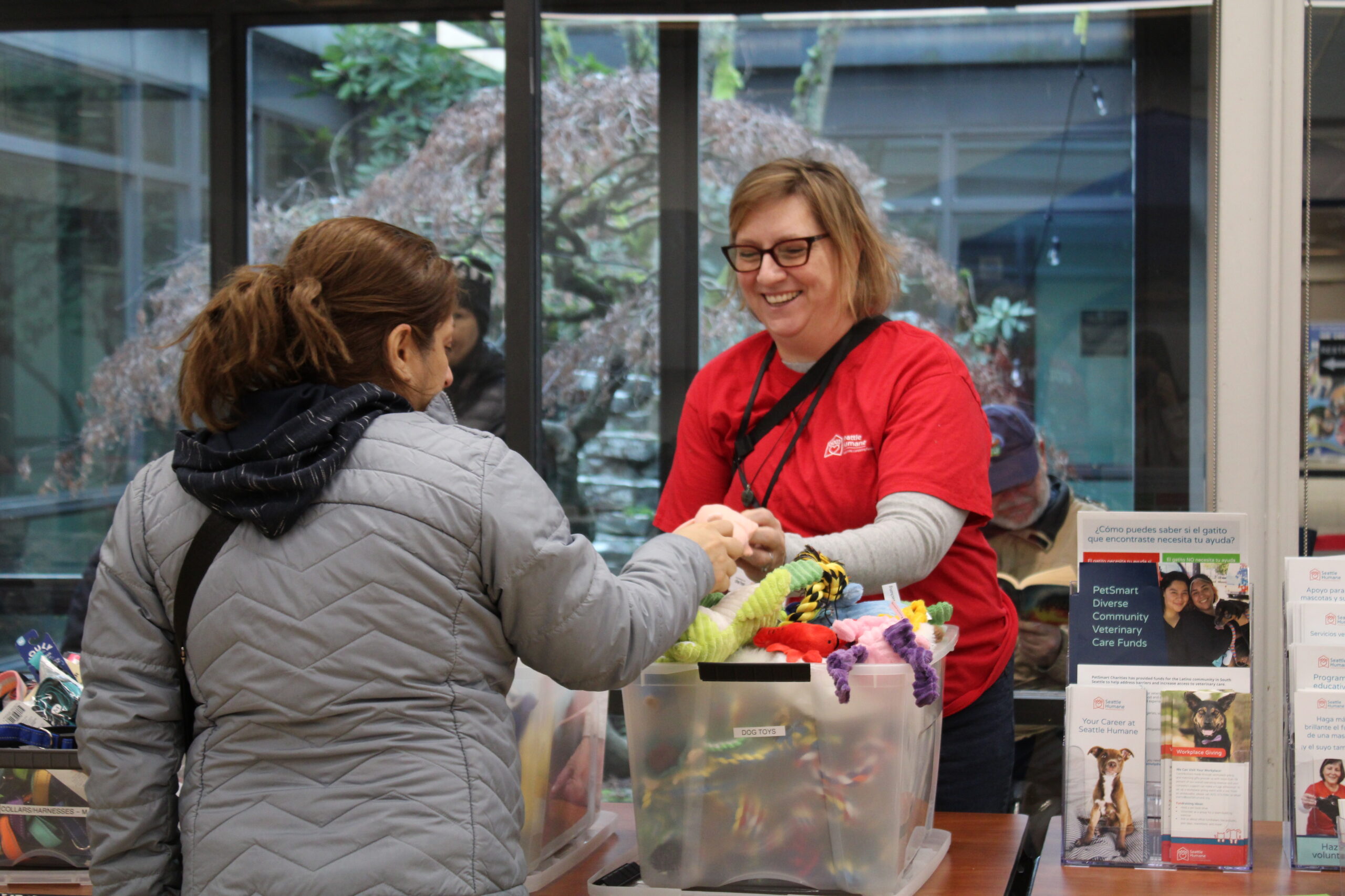 A Seattle Humane volunteer looks through pet toys with a client